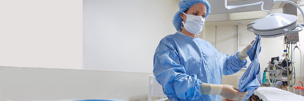 operating room nurse unfolding a surgical gown